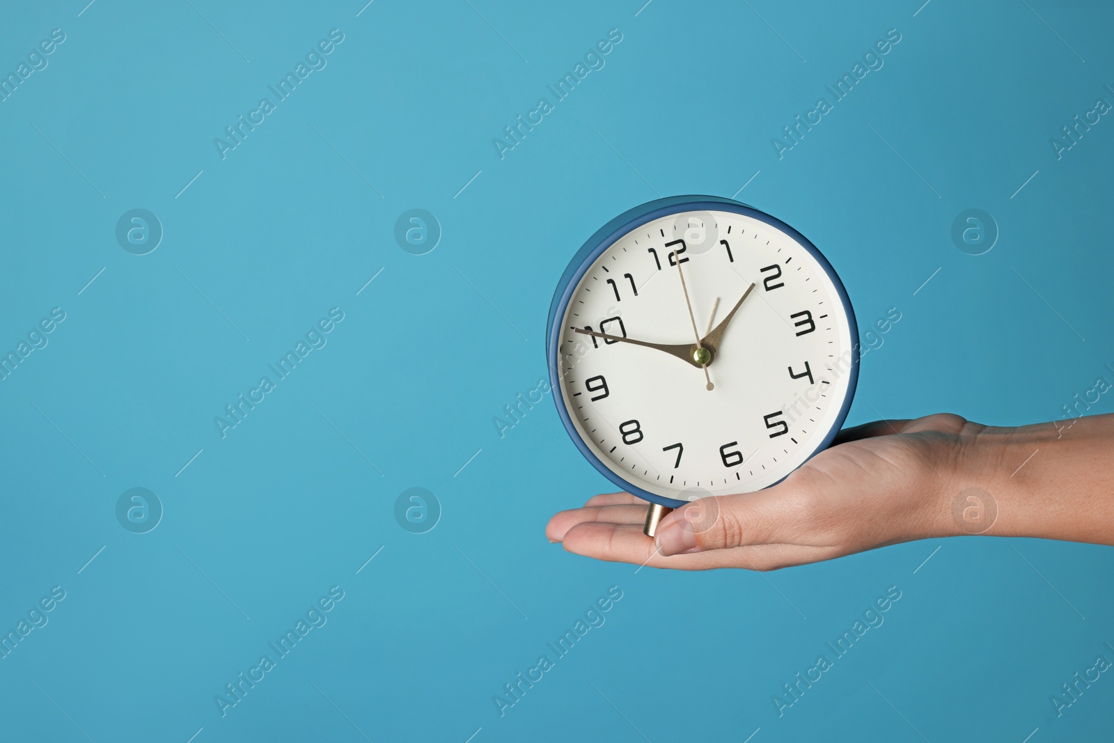 Photo of Woman with alarm clock on blue background, closeup. Space for text