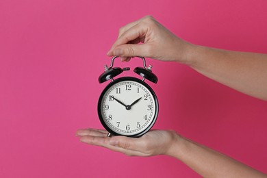 Woman with alarm clock on crimson background, closeup