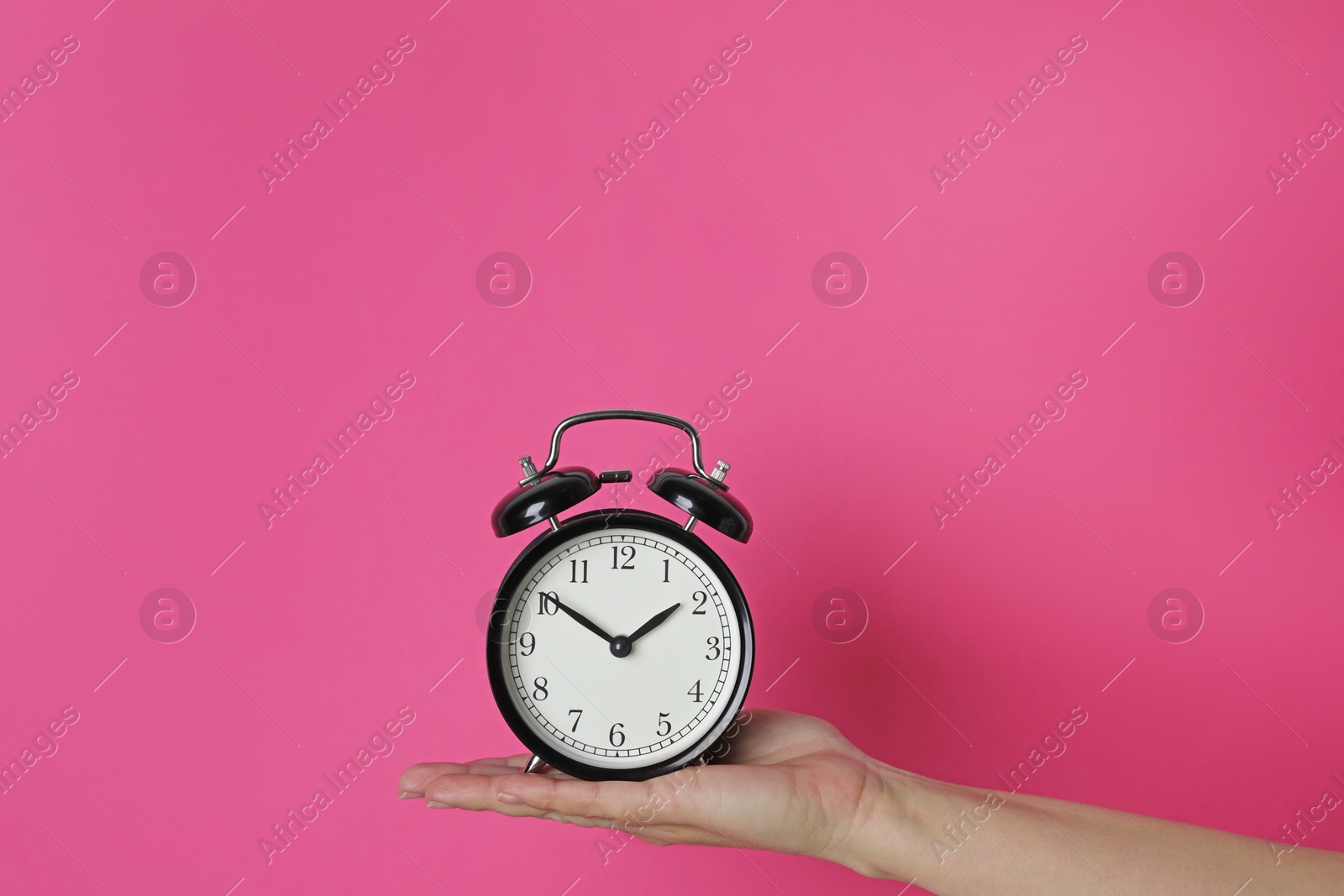 Photo of Woman with alarm clock on crimson background, closeup. Space for text