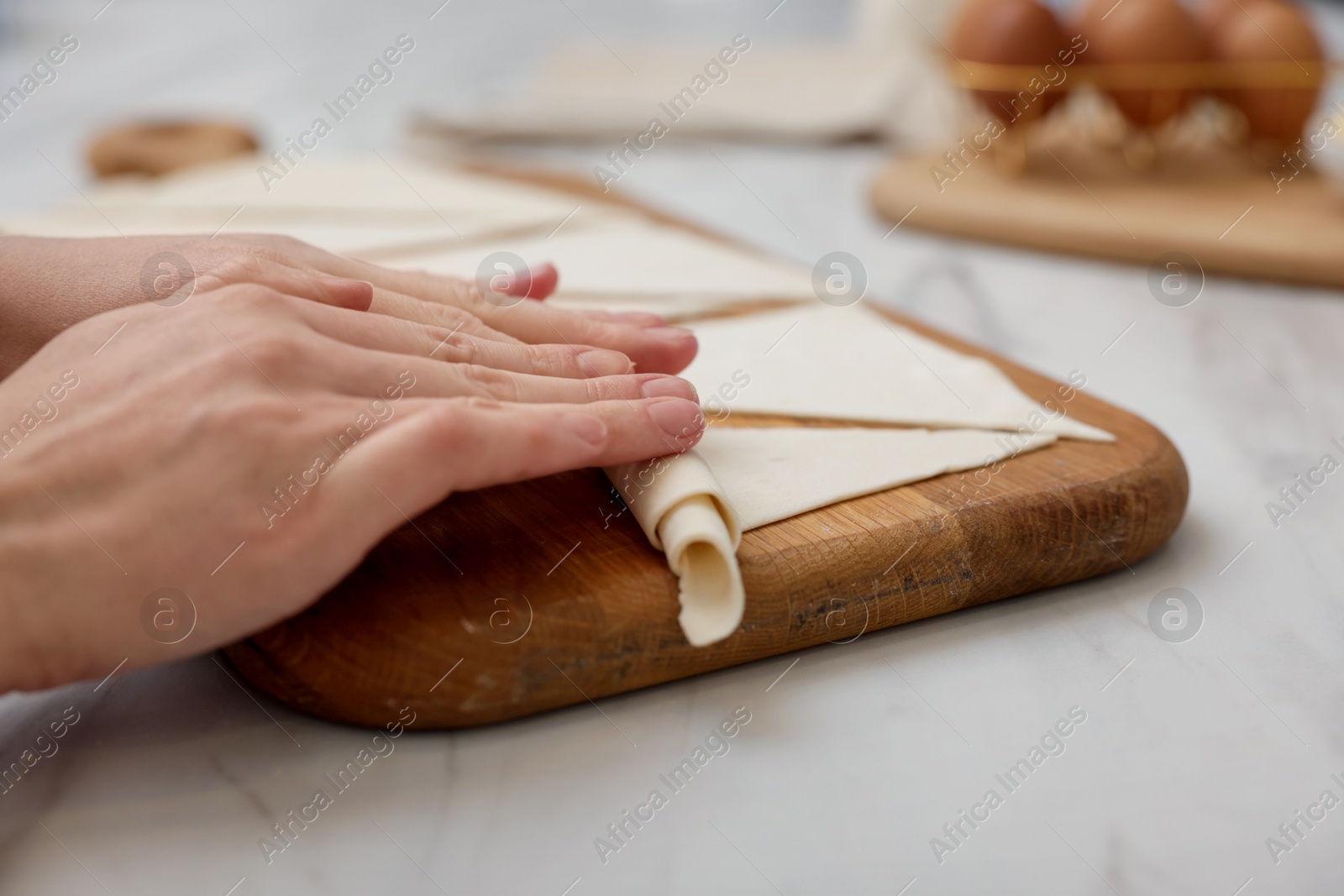 Woman rolling croissant from fresh dough at light marble table, closeup Photo of Woman rolling croissant from fresh dough at light marble table, closeup