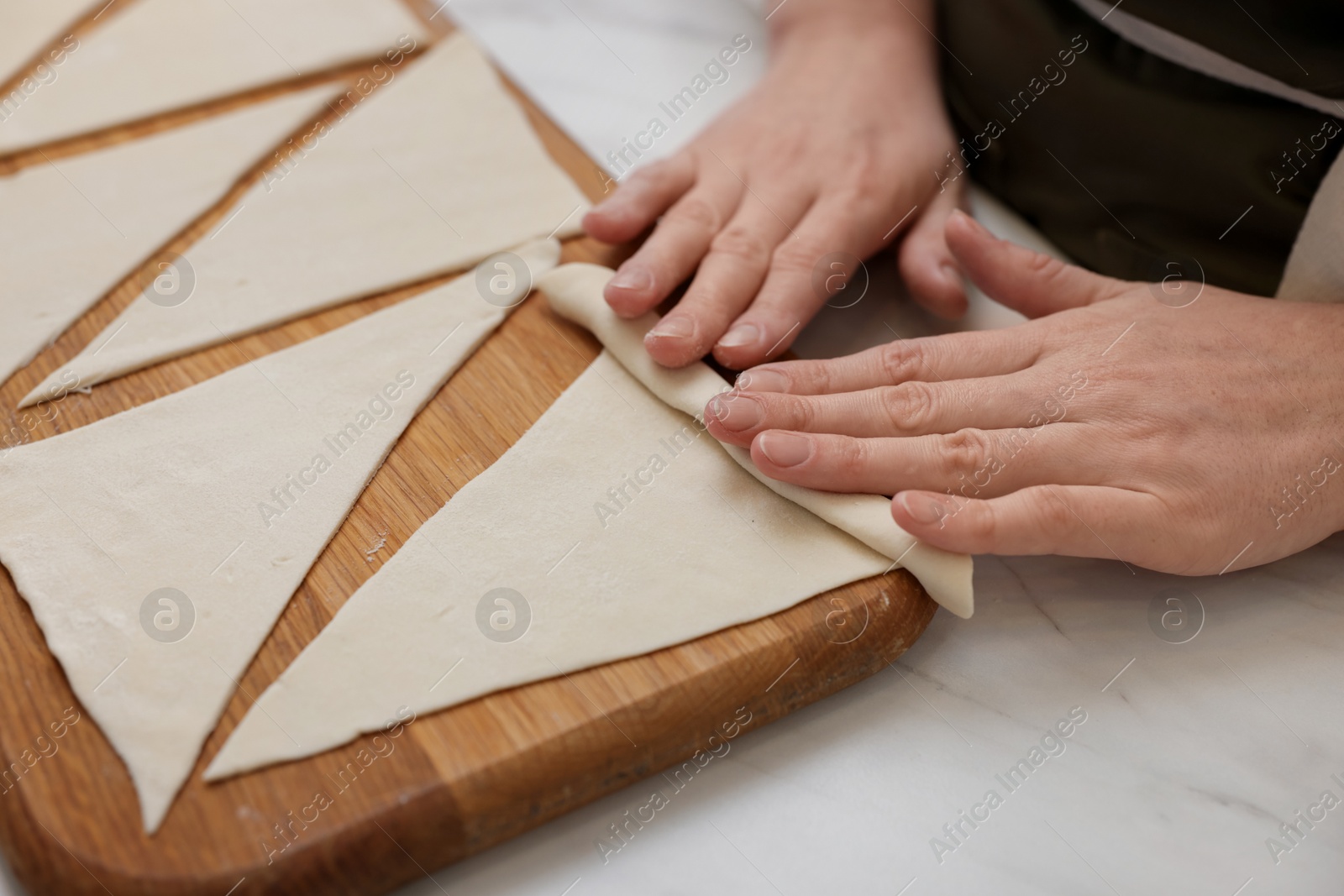 Woman rolling croissant from fresh dough at light marble table, closeup Photo of Woman rolling croissant from fresh dough at light marble table, closeup