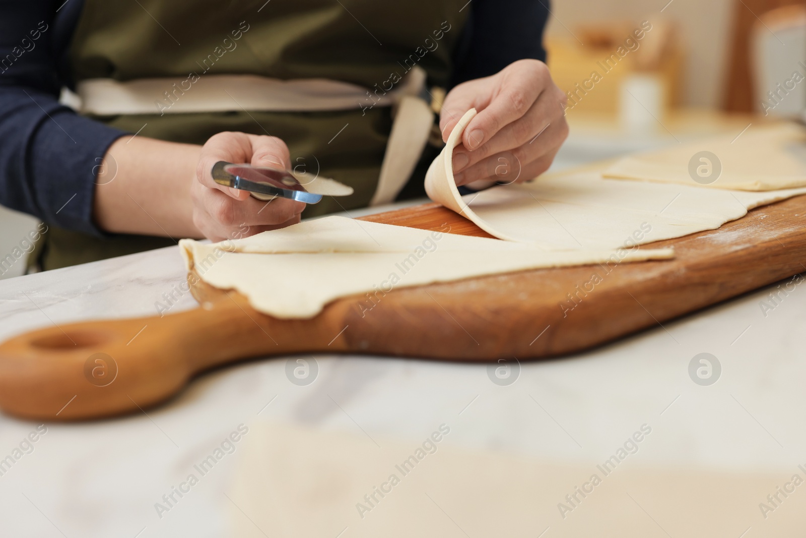 Woman cutting dough at light table, closeup. Making croissants Photo of Woman cutting dough at light table, closeup. Making croissants