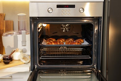 Freshly baked croissants on baking sheet in oven indoors, closeup