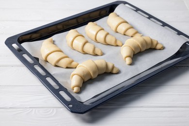 Photo of Raw croissants on white wooden table, closeup