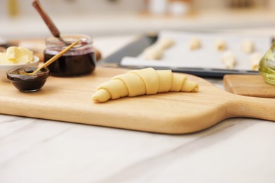 Photo of Raw croissant and ingredients on white marble table, closeup