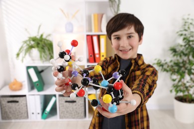 Boy with DNA structure model indoors, selective focus