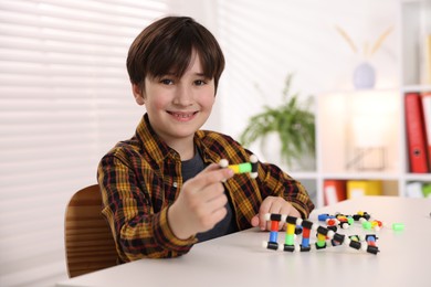 Boy making DNA structure model at desk indoors