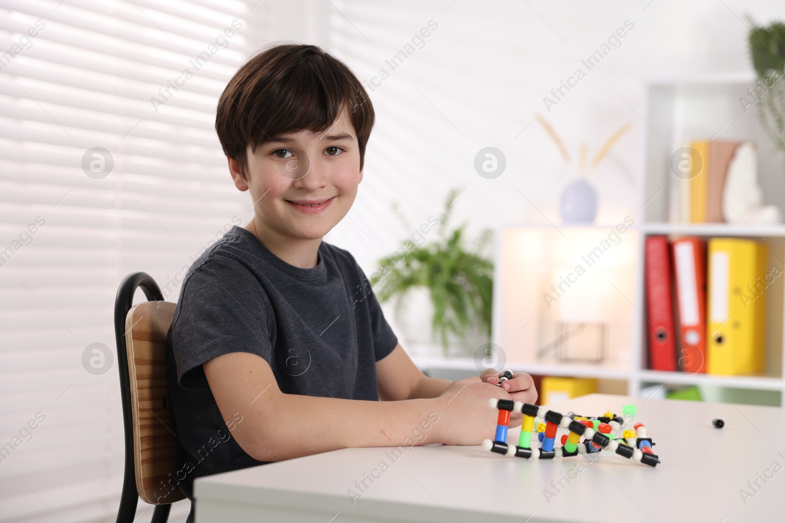 Photo of Boy making DNA structure model at desk indoors