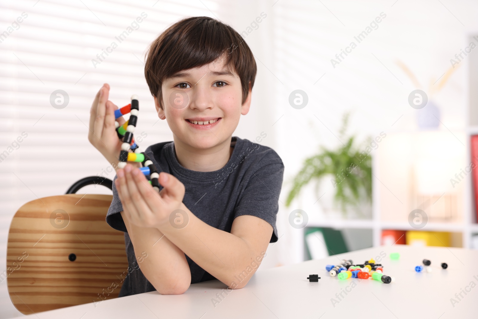 Photo of Boy with DNA structure model at desk indoors