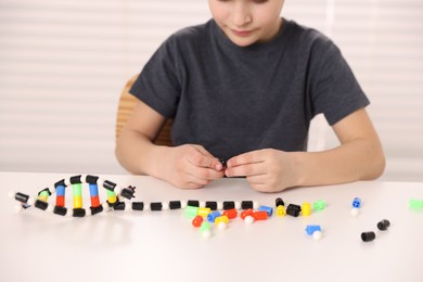 Photo of Boy making DNA structure model at desk indoors, closeup