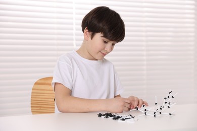 Photo of Boy making DNA structure model at desk indoors