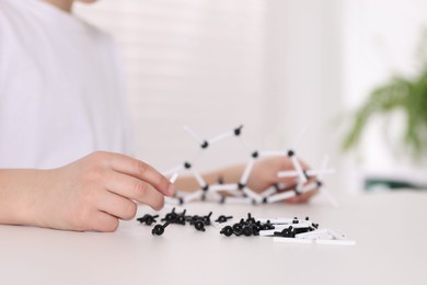 Photo of Boy making DNA structure model at desk indoors, closeup. Space for text