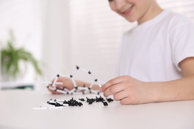 Photo of Boy making DNA structure model at desk indoors, closeup. Space for text