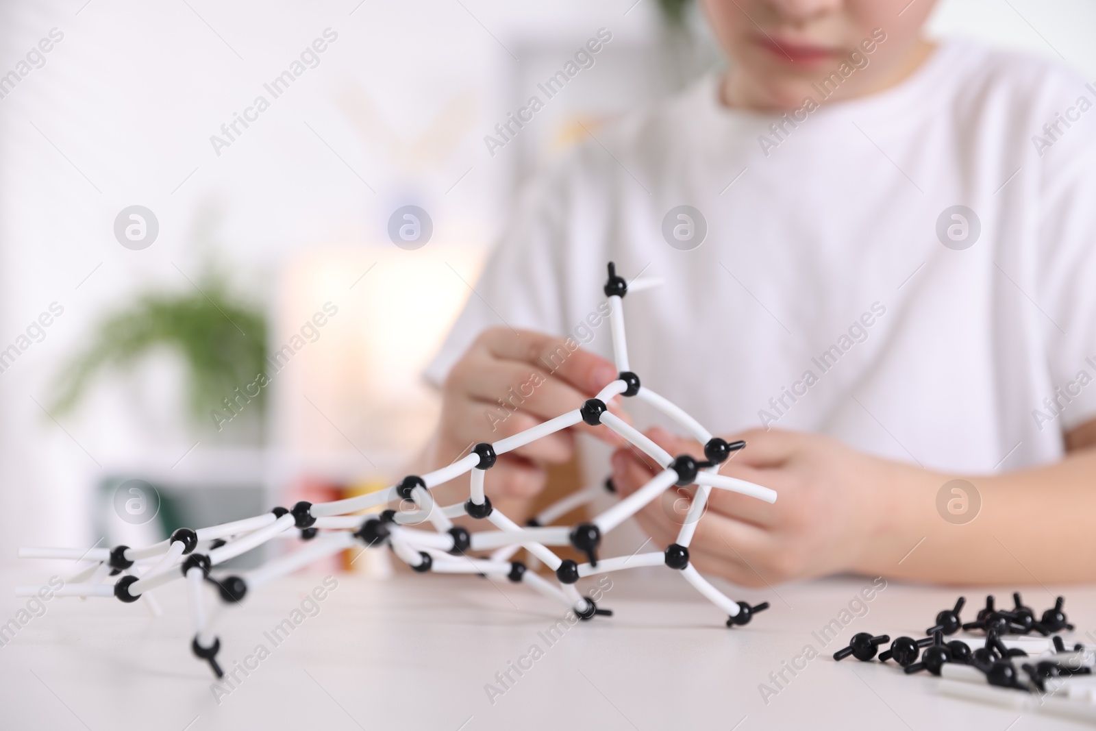 Photo of Boy making DNA structure model at desk indoors, closeup. Space for text