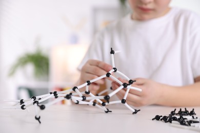 Boy making DNA structure model at desk indoors, closeup. Space for text