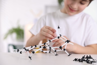 Photo of Boy making DNA structure model at desk indoors, closeup. Space for text