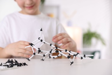 Boy making DNA structure model at desk indoors, closeup. Space for text