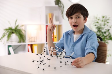 Boy making DNA structure model at desk indoors. Space for text