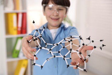 Boy with DNA structure model indoors, selective focus