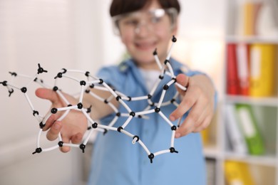 Boy with DNA structure model indoors, selective focus