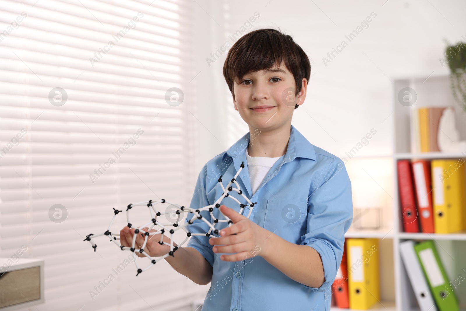 Photo of Smiling boy with DNA structure model indoors. Space for text