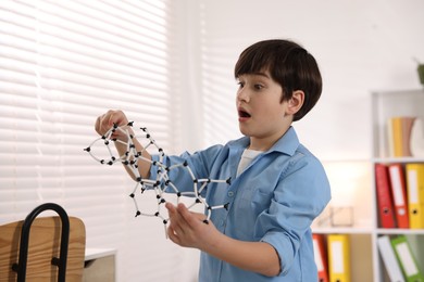 Emotional boy with DNA structure model indoors