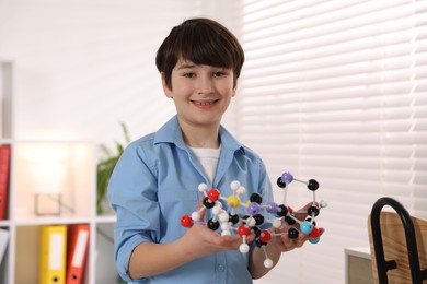 Smiling boy with DNA structure model indoors