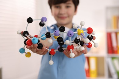 Boy with DNA structure model indoors, selective focus