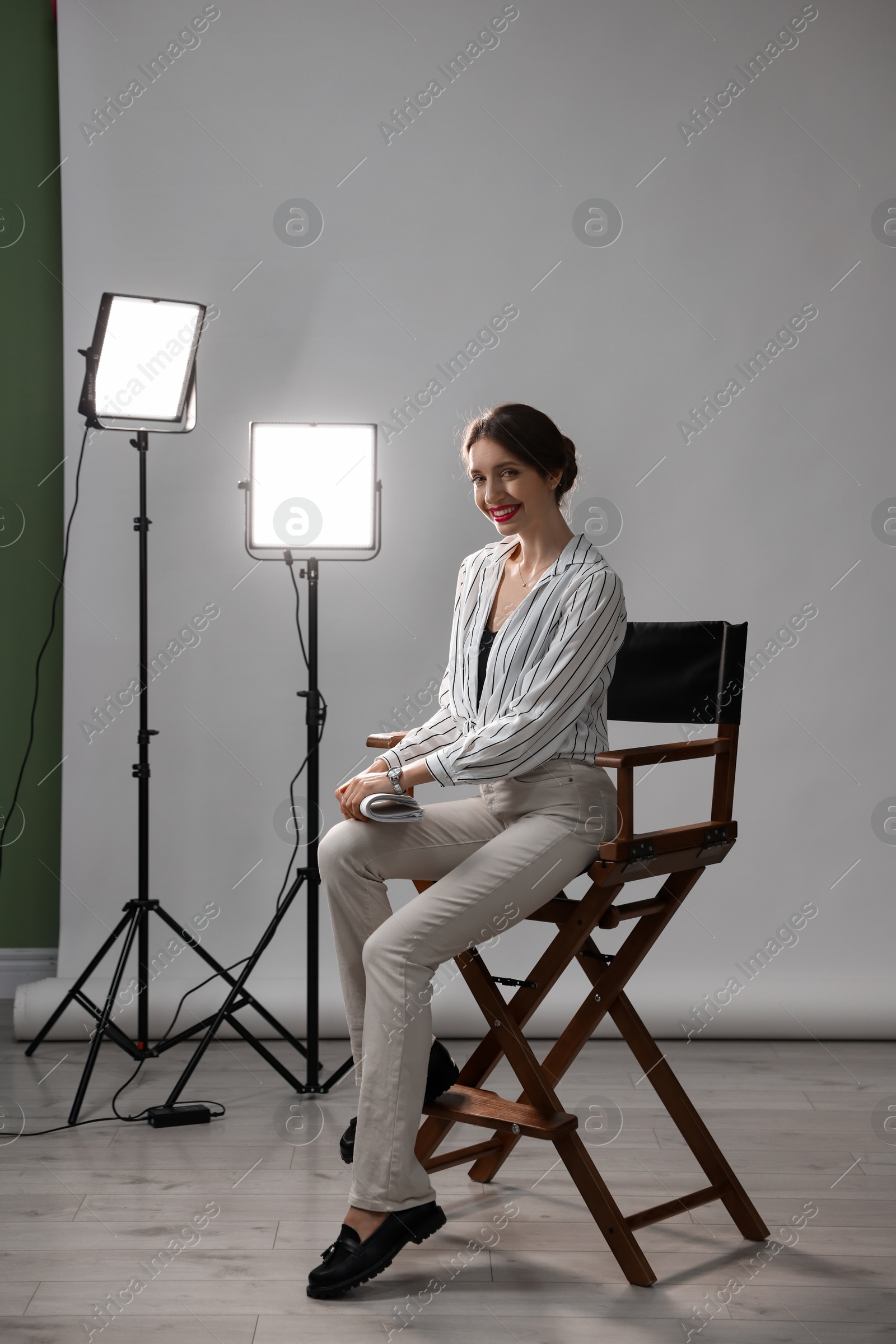 Photo of Beautiful woman with script sitting in director's chair in studio