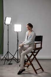 Photo of Beautiful woman with script sitting in director's chair in studio