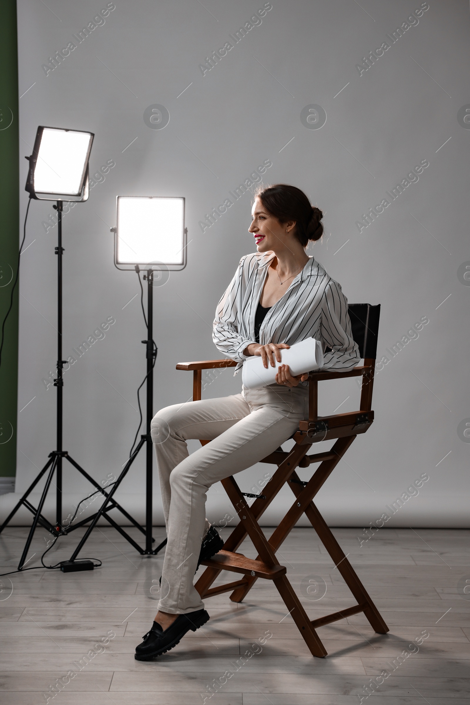 Photo of Beautiful woman with script sitting in director's chair in studio