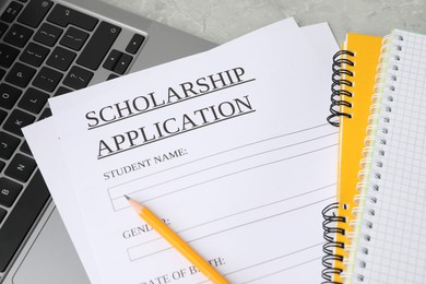 Photo of Scholarship application form, notebooks, pencil and laptop on grey table, above view