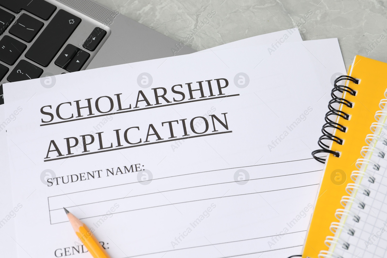 Photo of Scholarship application form, notebooks, pencil and laptop on grey table, above view