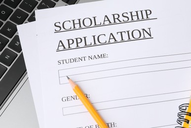 Photo of Scholarship application form, pencil and laptop on table, top view