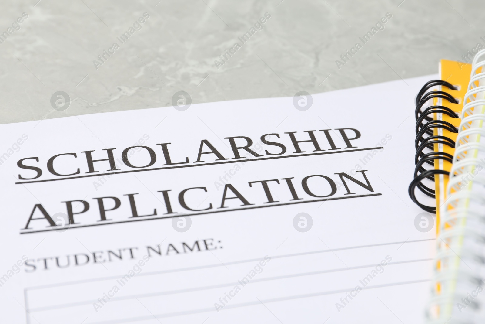 Photo of Scholarship application form and notebooks on grey marble table, closeup