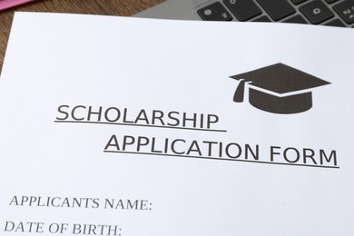 Photo of Scholarship application form and laptop on table, closeup