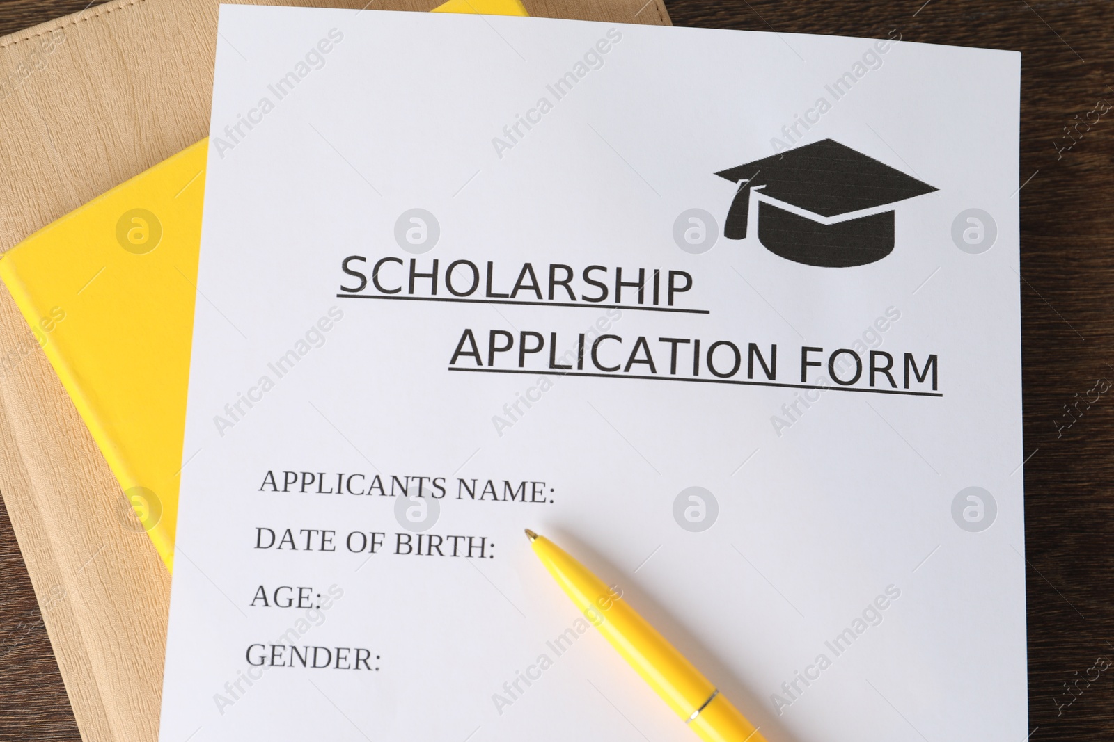 Photo of Scholarship application form, pen and notebooks on table, top view