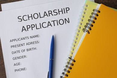 Photo of Scholarship application form, pen and notebooks on table, flat lay