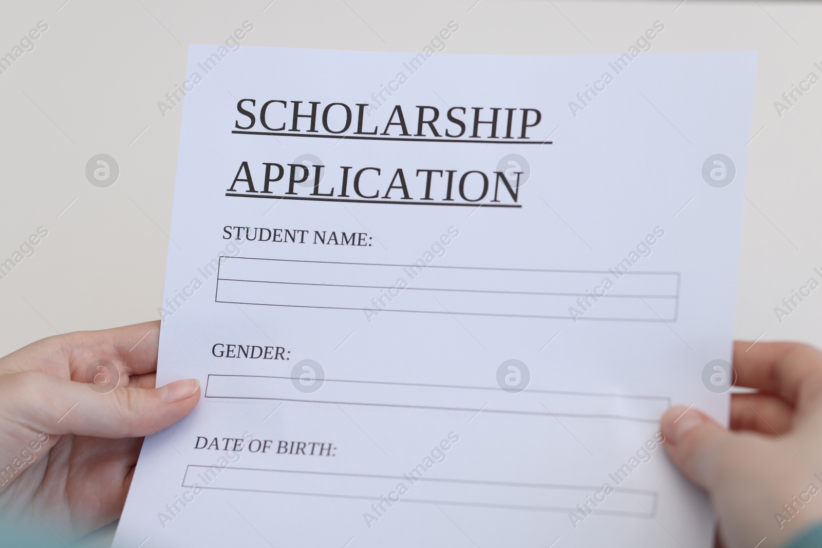 Photo of Student with scholarship application forms at white table, closeup