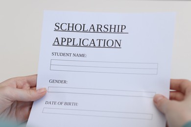 Student with scholarship application forms at white table, closeup