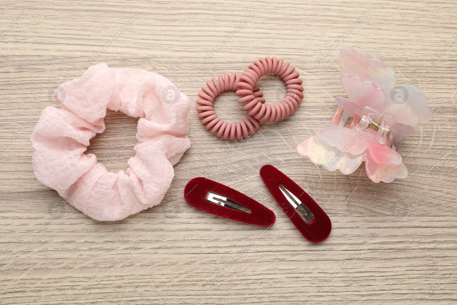 Photo of Different hair accessories on wooden table, flat lay