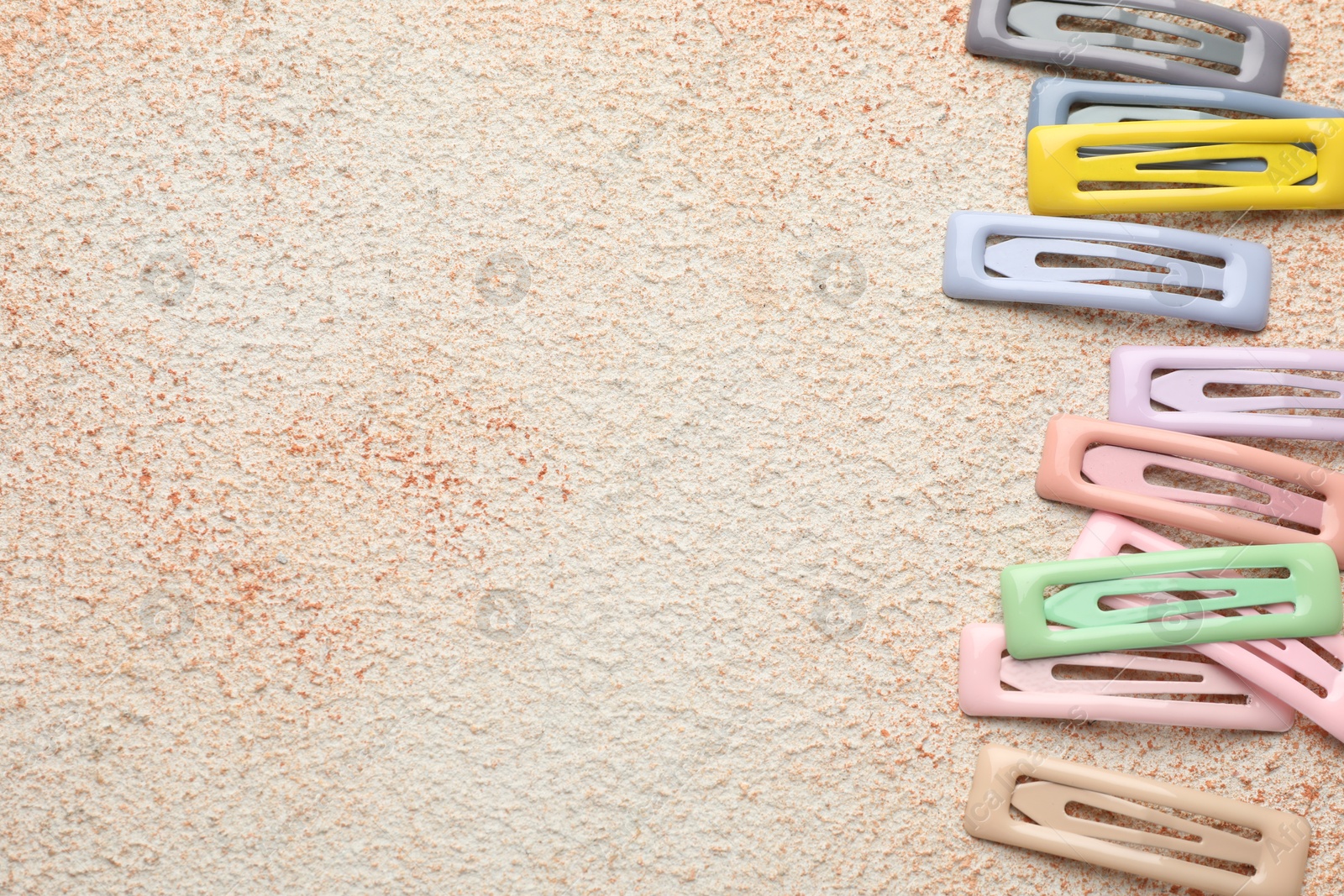 Photo of Different hair clips on color textured table, flat lay. Space for text