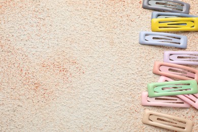 Different hair clips on color textured table, flat lay. Space for text