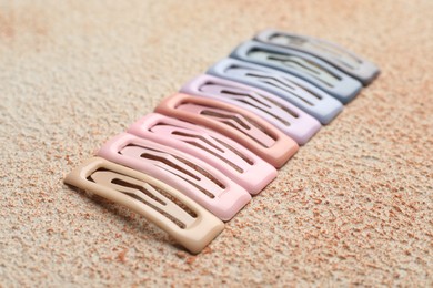 Different hair clips on color textured table, closeup