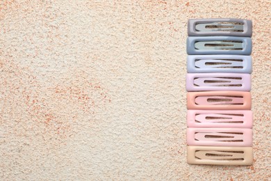 Photo of Different hair clips on color textured table, flat lay. Space for text