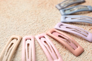 Different hair clips on color textured table, closeup