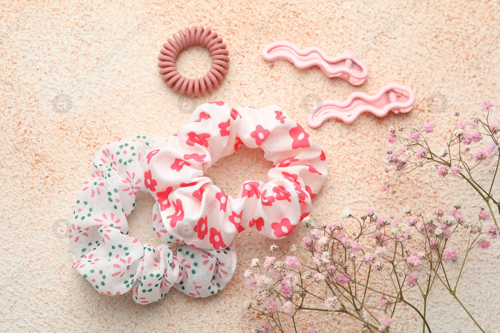 Photo of Different hair accessories and gypsophila flowers on color textured table, flat lay