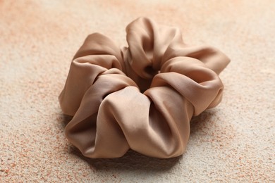 Photo of Beautiful hair scrunchie on color textured table, closeup