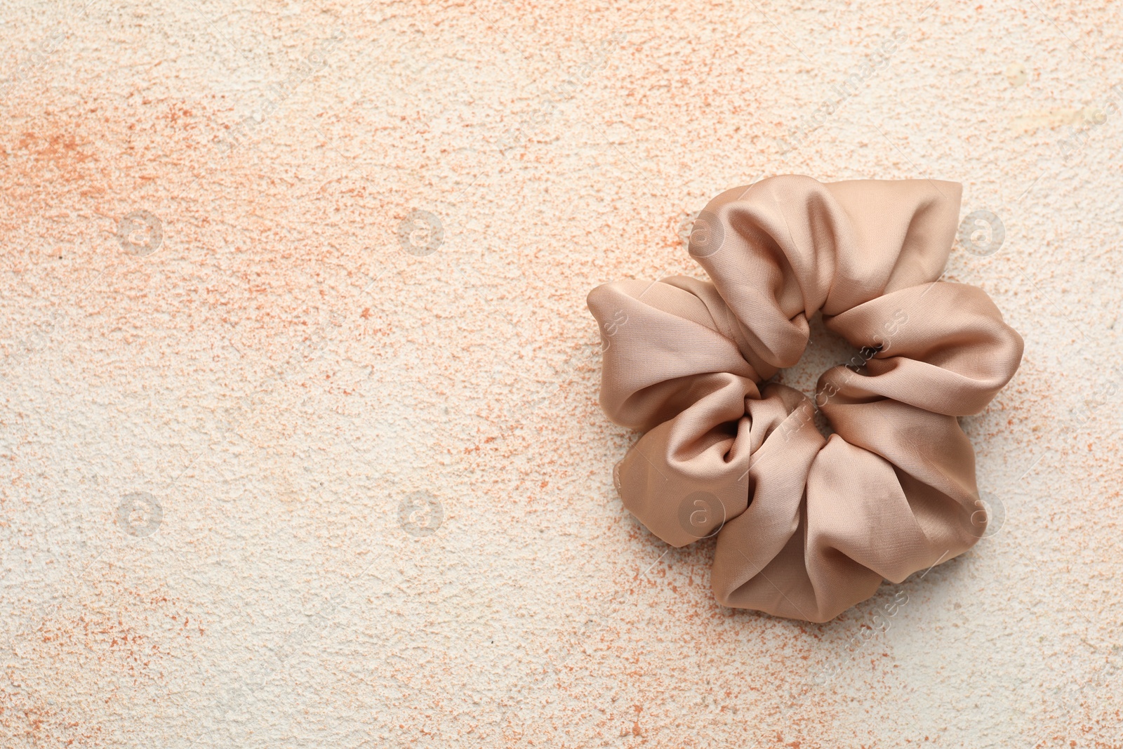 Photo of Beautiful hair scrunchie on color textured table, top view. Space for text