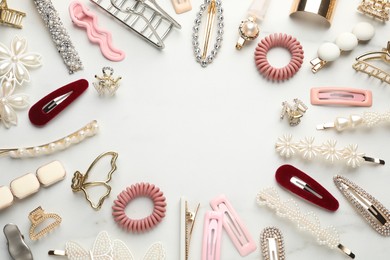 Frame of different hair accessories on white marble table, flat lay. Space for text